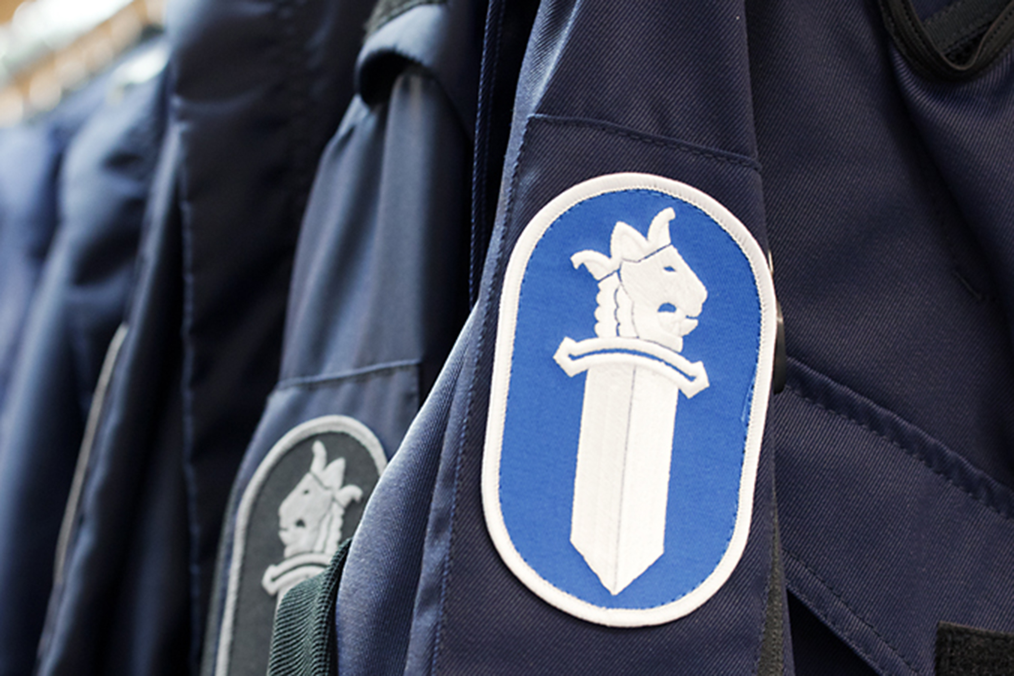 Sleeve badges on police overalls showing the emblem of the Finnish police.