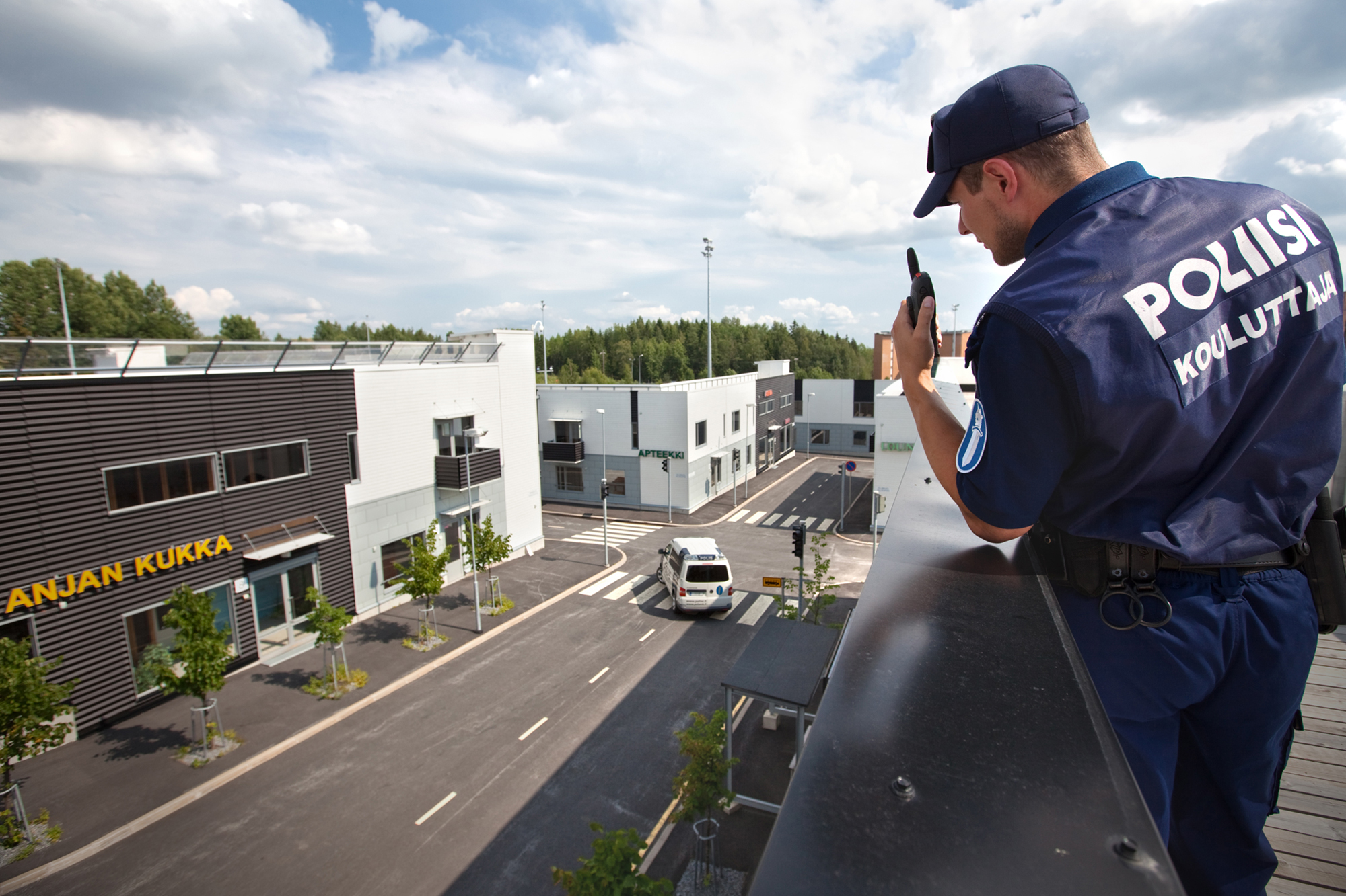 En polisutbildare ser ner på vad som händer i Polisyrkeshögskolans övningsområde från observationsområdet på taket.