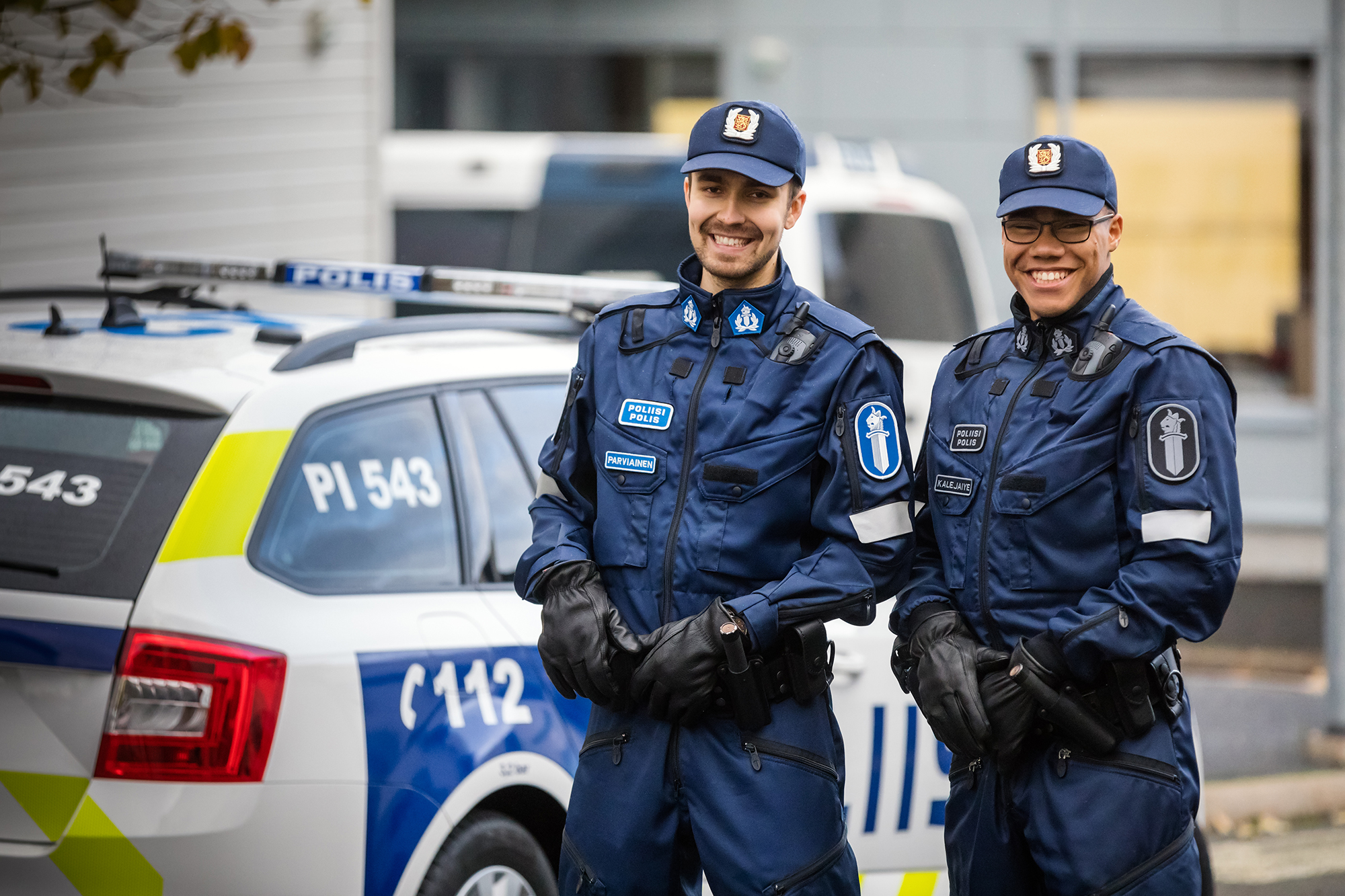 Två polisstuderande i uniform framför en polisbil.