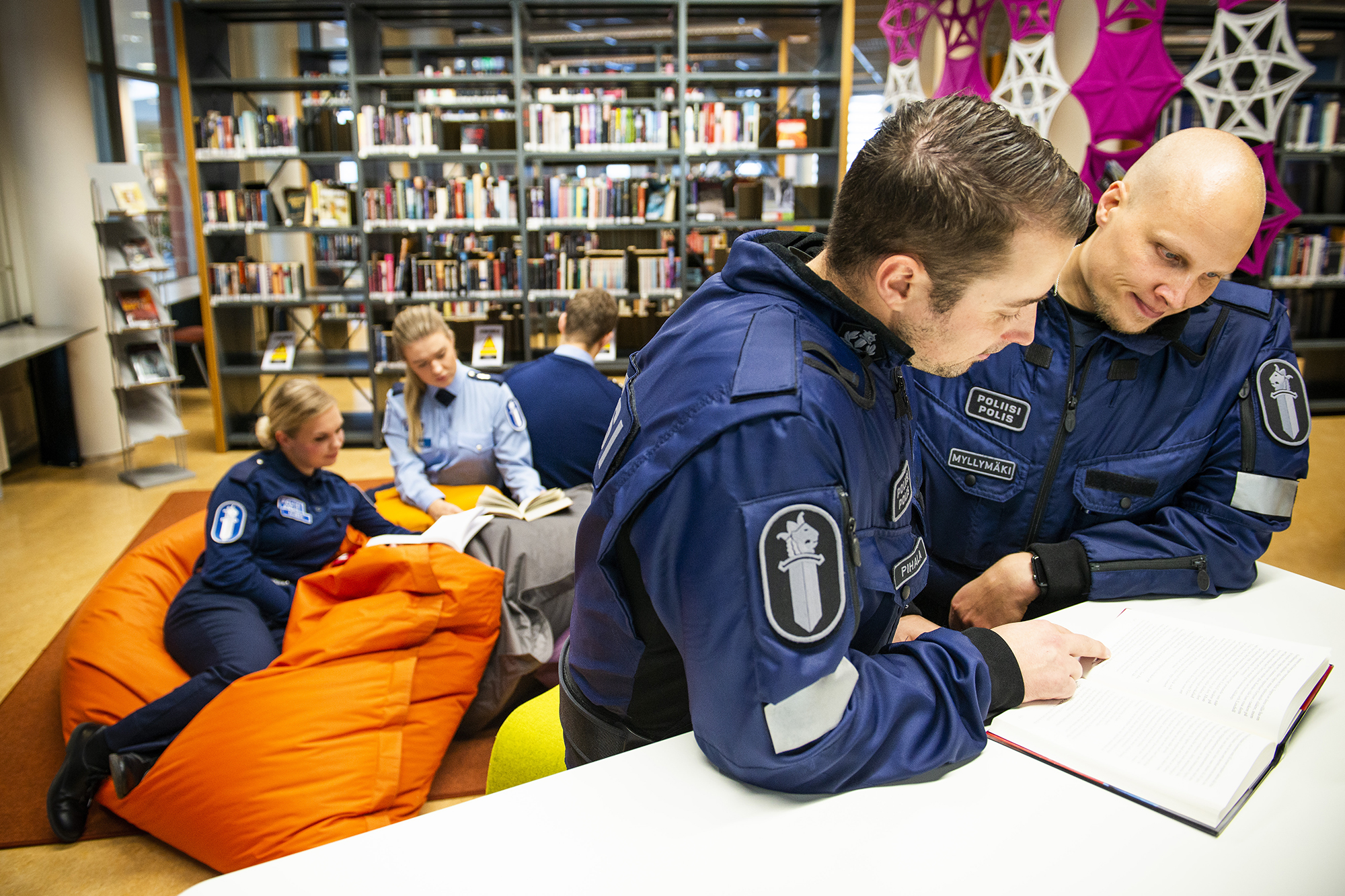 Viisi virkapukuista poliisiopiskelijaa lukee Poliisiammattikorkeakoulun kirjastossa.