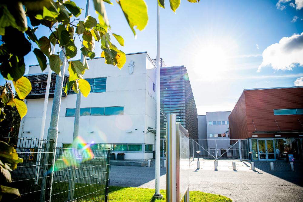 The facade of the Police University College viewed from behind the trees.