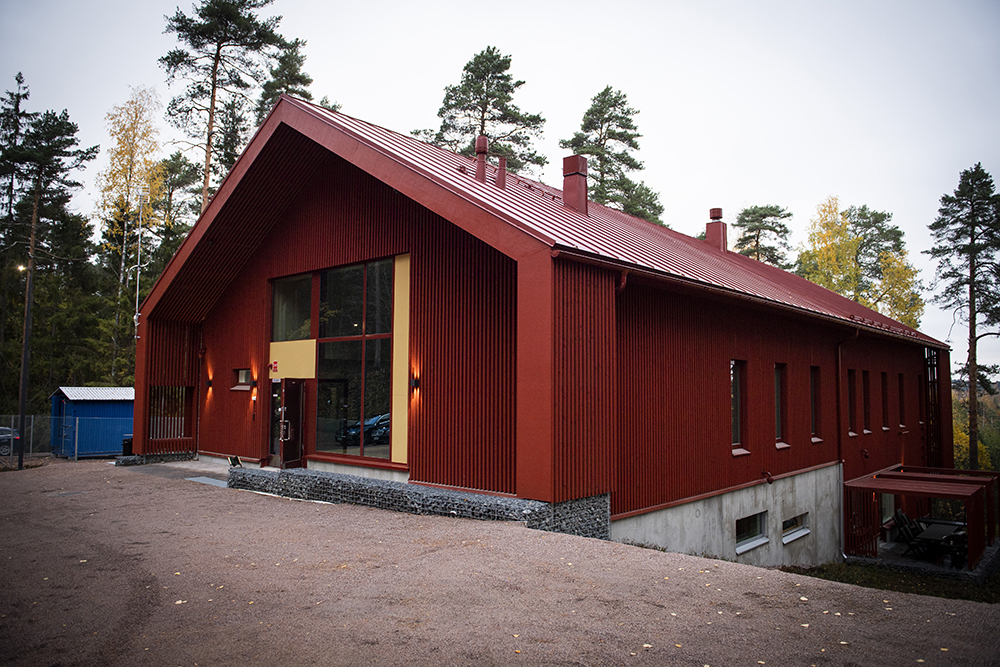 Red wooden building, trees in the background.